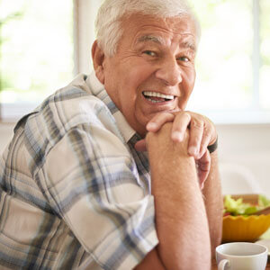 Old man smiling at table